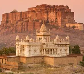View of the white marble Jaswant Thada memorial with Mehrangarh Fort towering behind it in Jodhpur at sunset, illustrating Jodhpur sightseeing highlights.