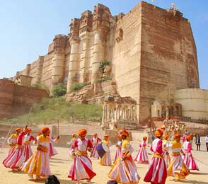 Traditional folk dancers performing in front of the massive Mehrangarh Fort in Jodhpur, illustrating cultural sightseeing experiences offered in Jodhpur tour packages.